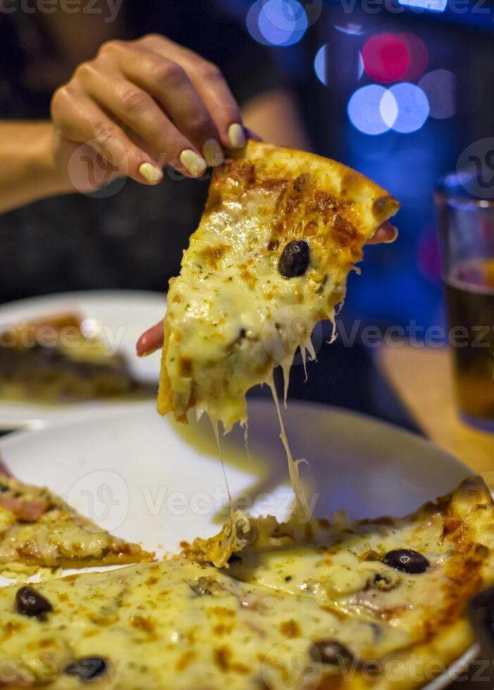 a slice of pizza in his hand a restaurant beautiful background photo