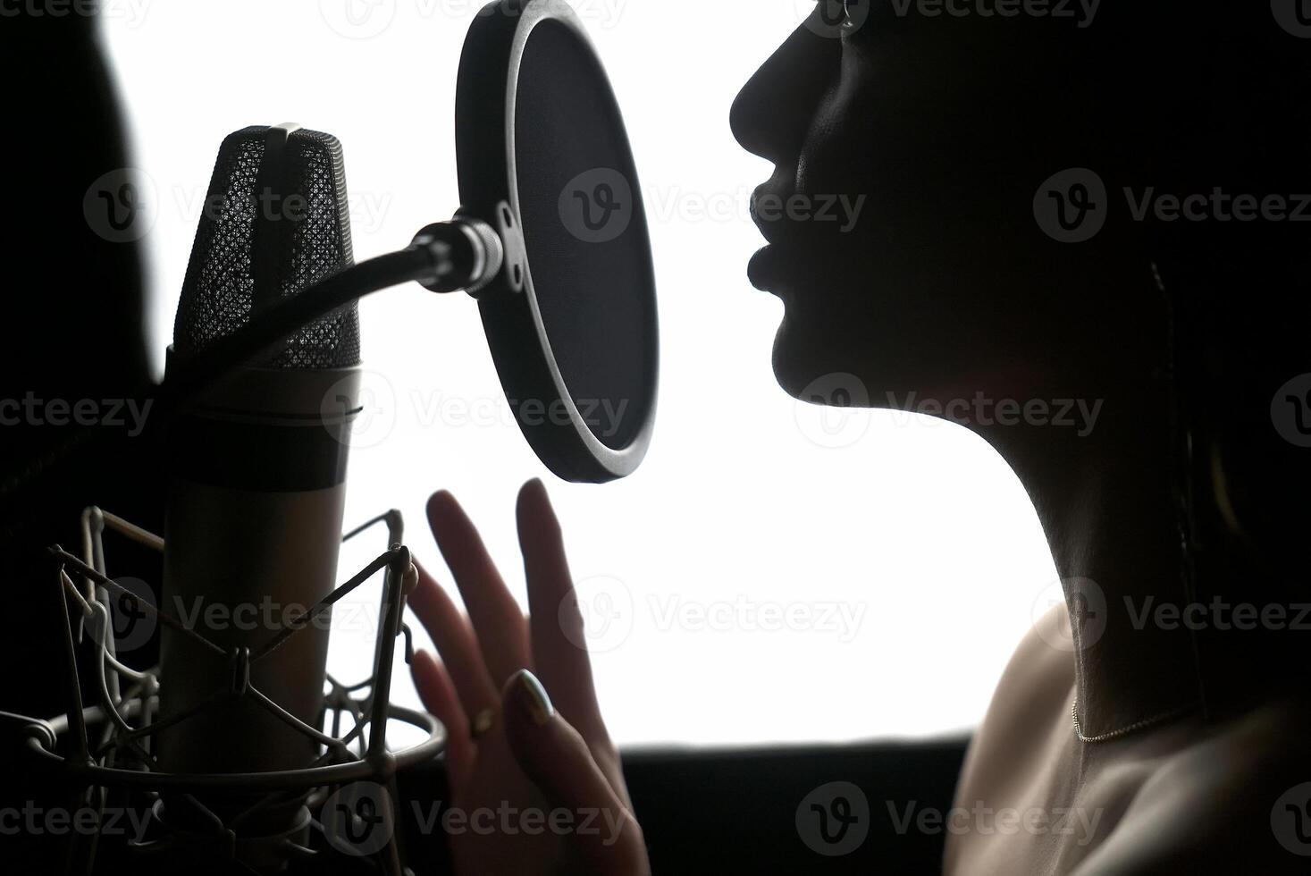 Girl singing to the microphone in a studio. Female vocal. Black and White. photo