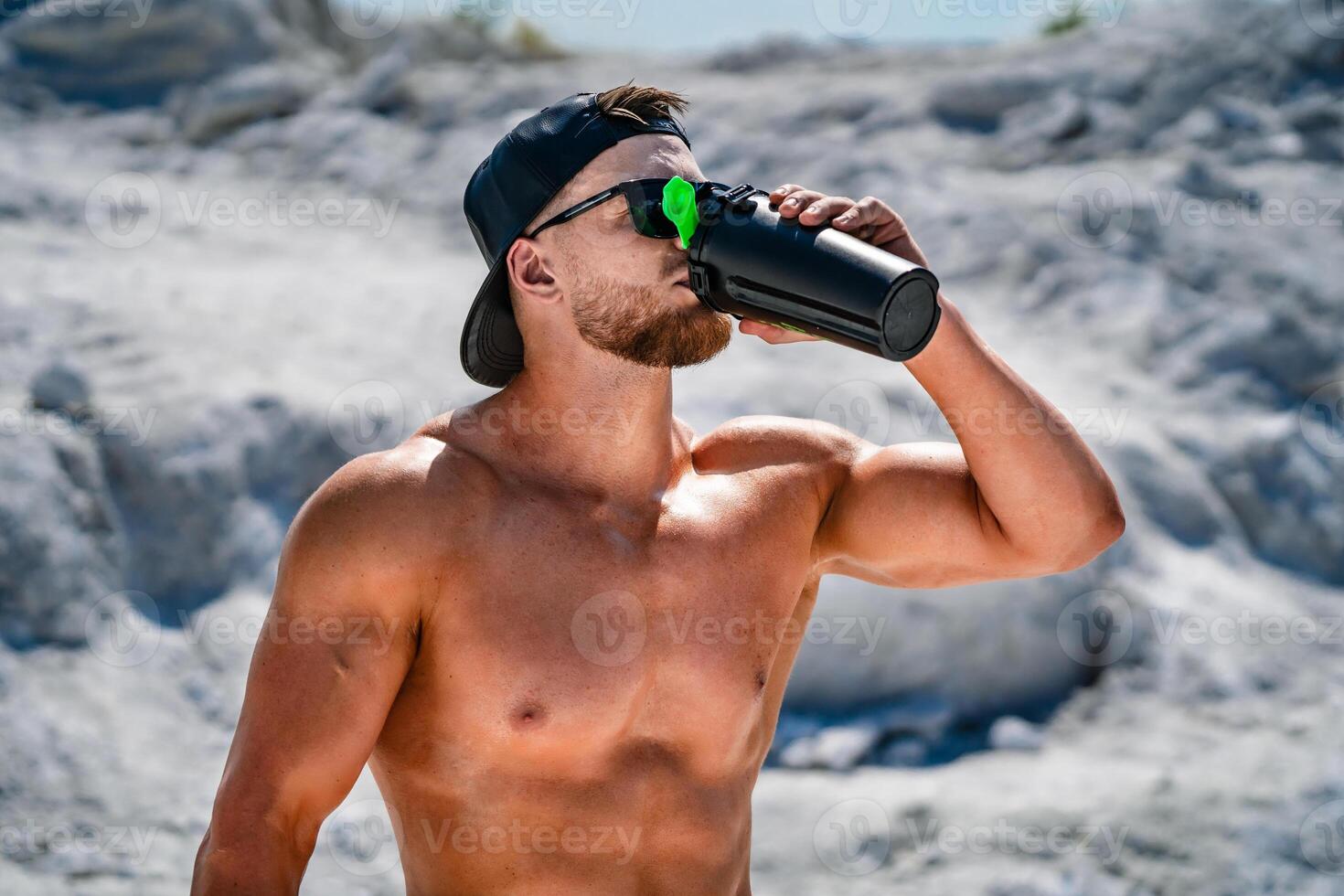 retrato de un hermoso medio desnudo carrocero hombre en un montaña con un botella de agua. foto