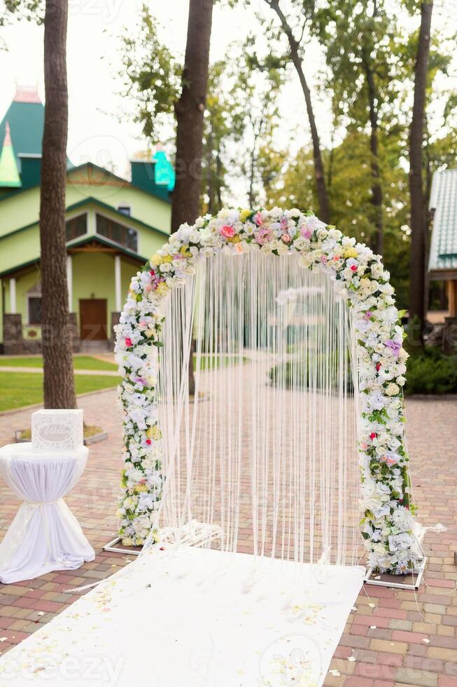 Wedding ceremony decoration. White arch with flowers concept. Closeup. photo