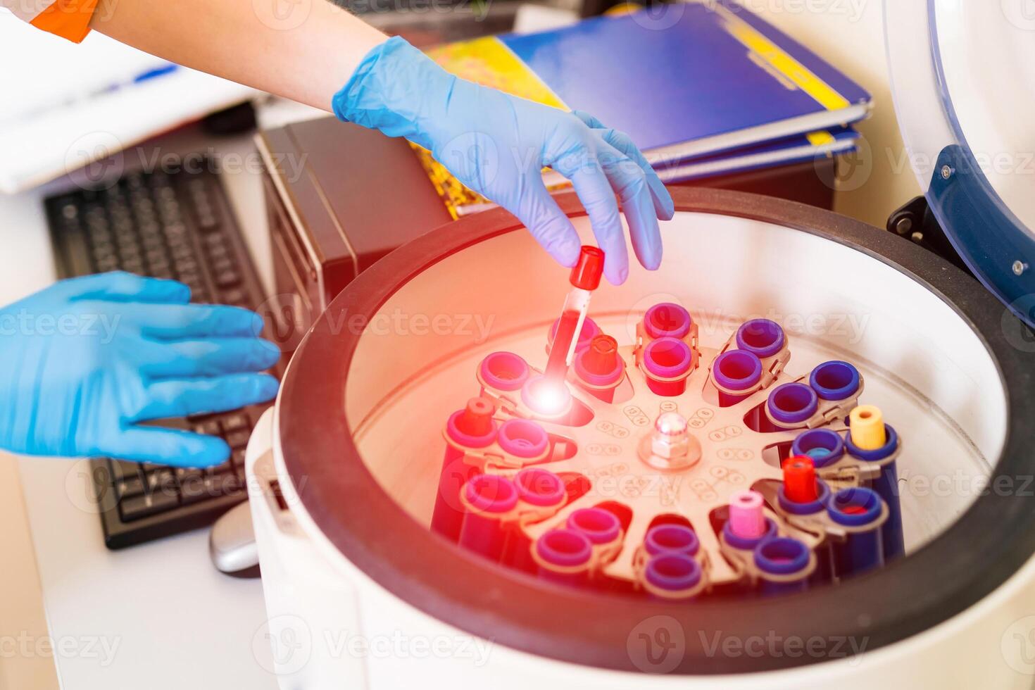 médico poniendo tubos de sangre en centrífugo máquina para pruebas y analizando foto
