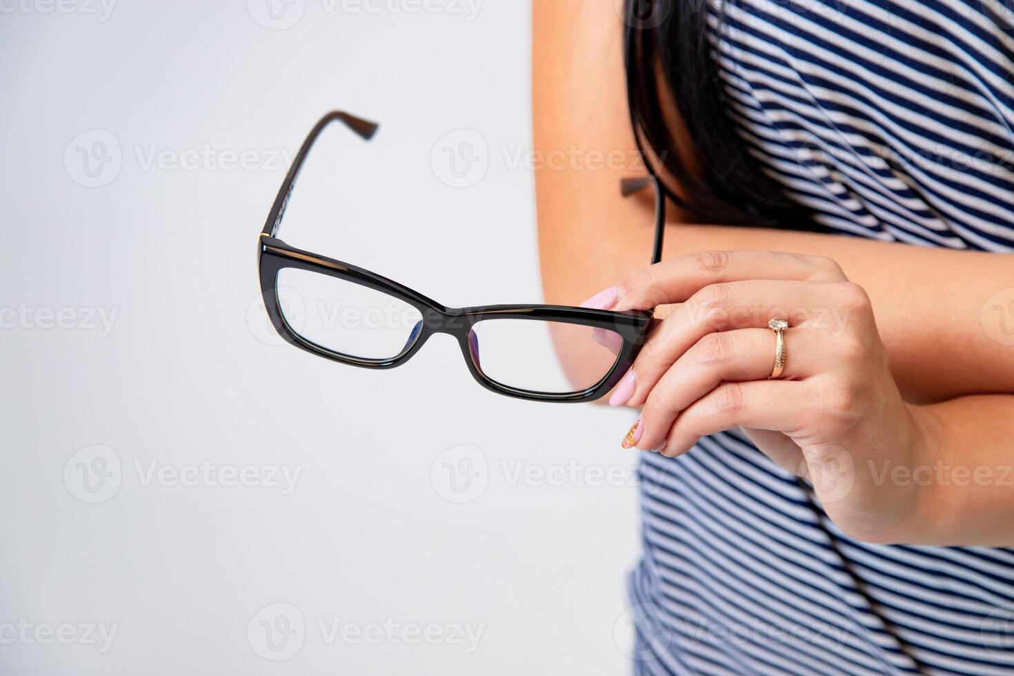 hand of woman holds trendy glasses with black rim on a white background in the studio. Close-up photo