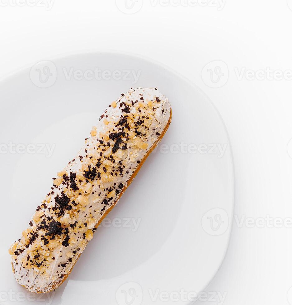 Eclair with cream and chocolate on plate photo