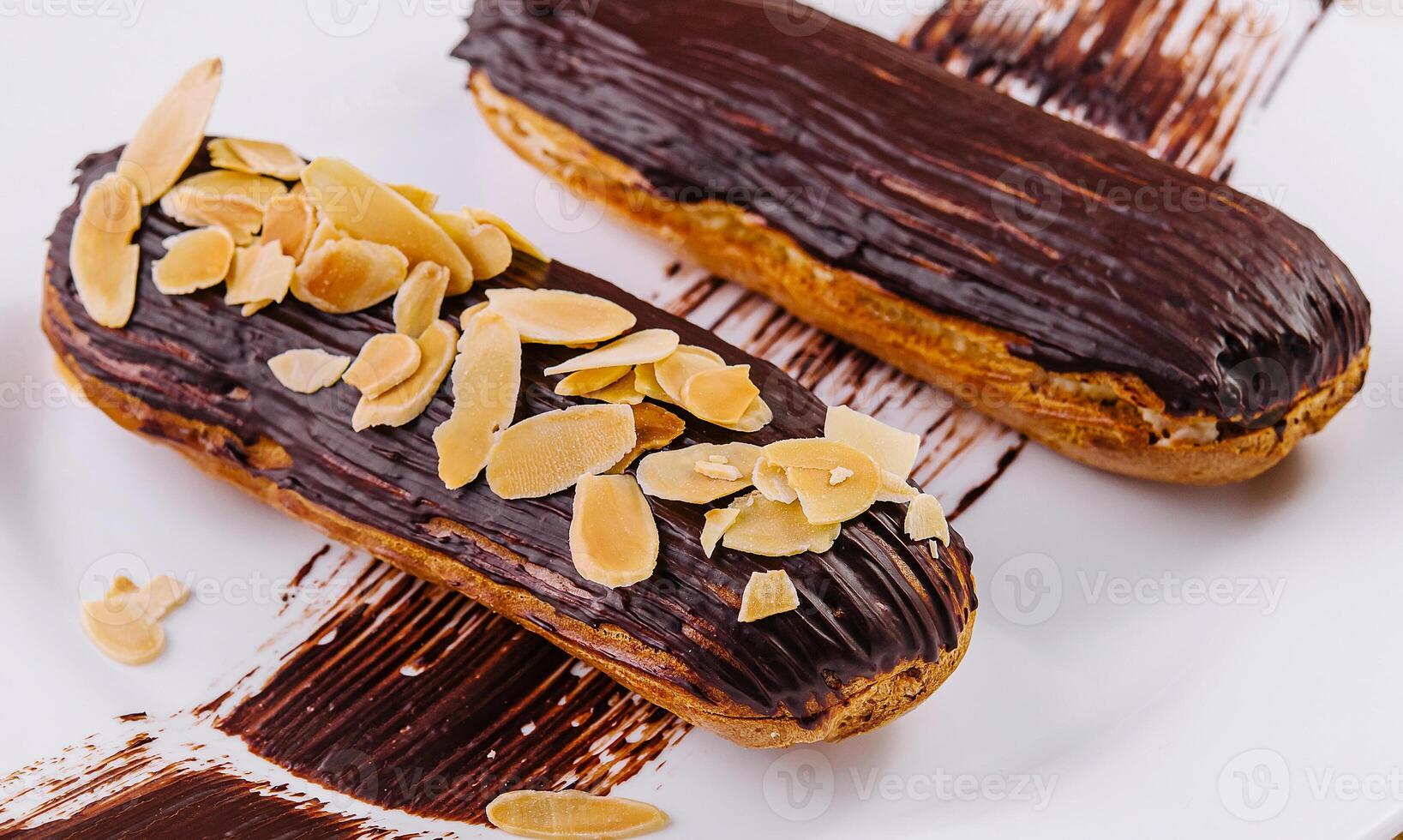 Chocolate eclairs with almonds on plate photo