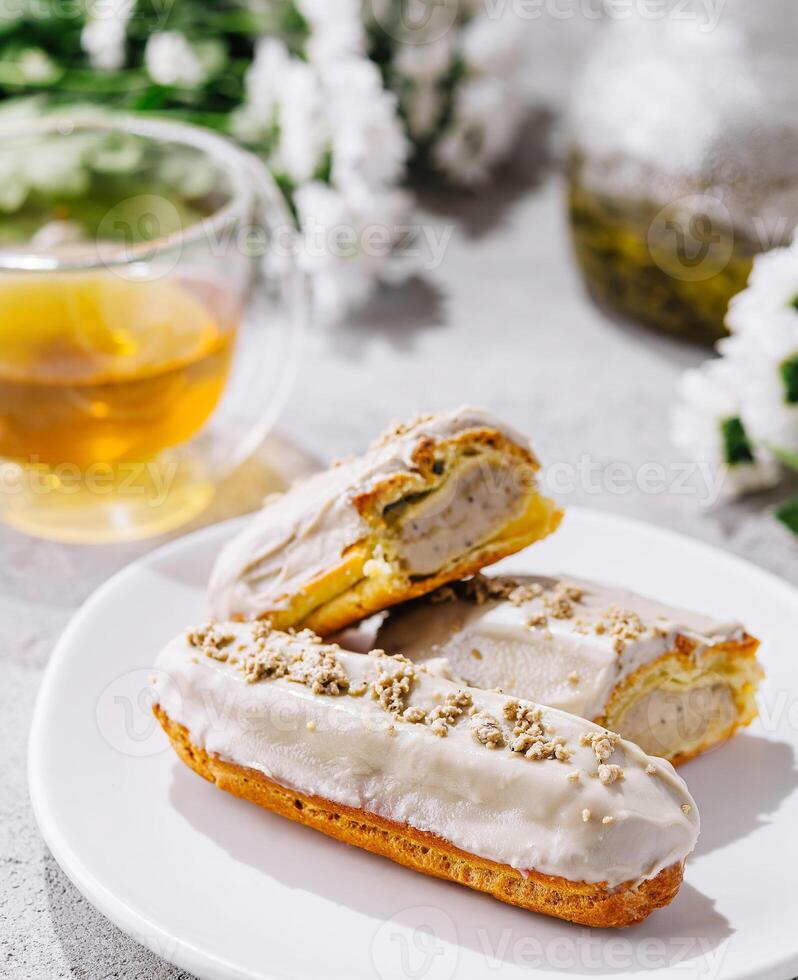 eclairs with white glaze and poppy seeds and tea photo