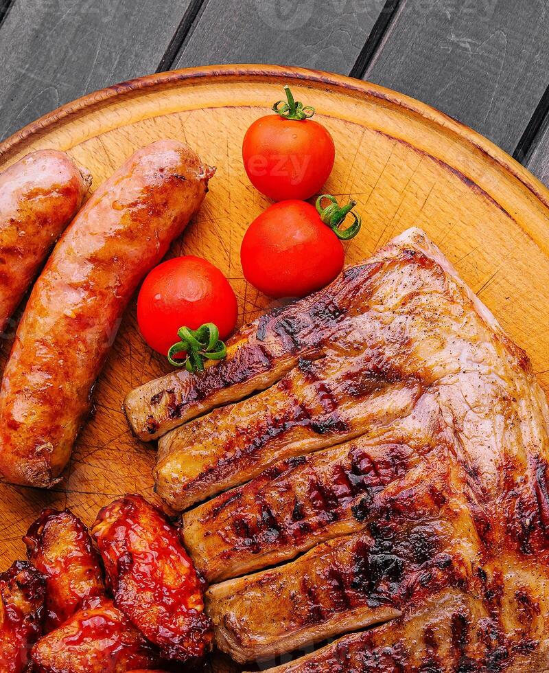 pork ribs with chicken and sausages on wooden board photo