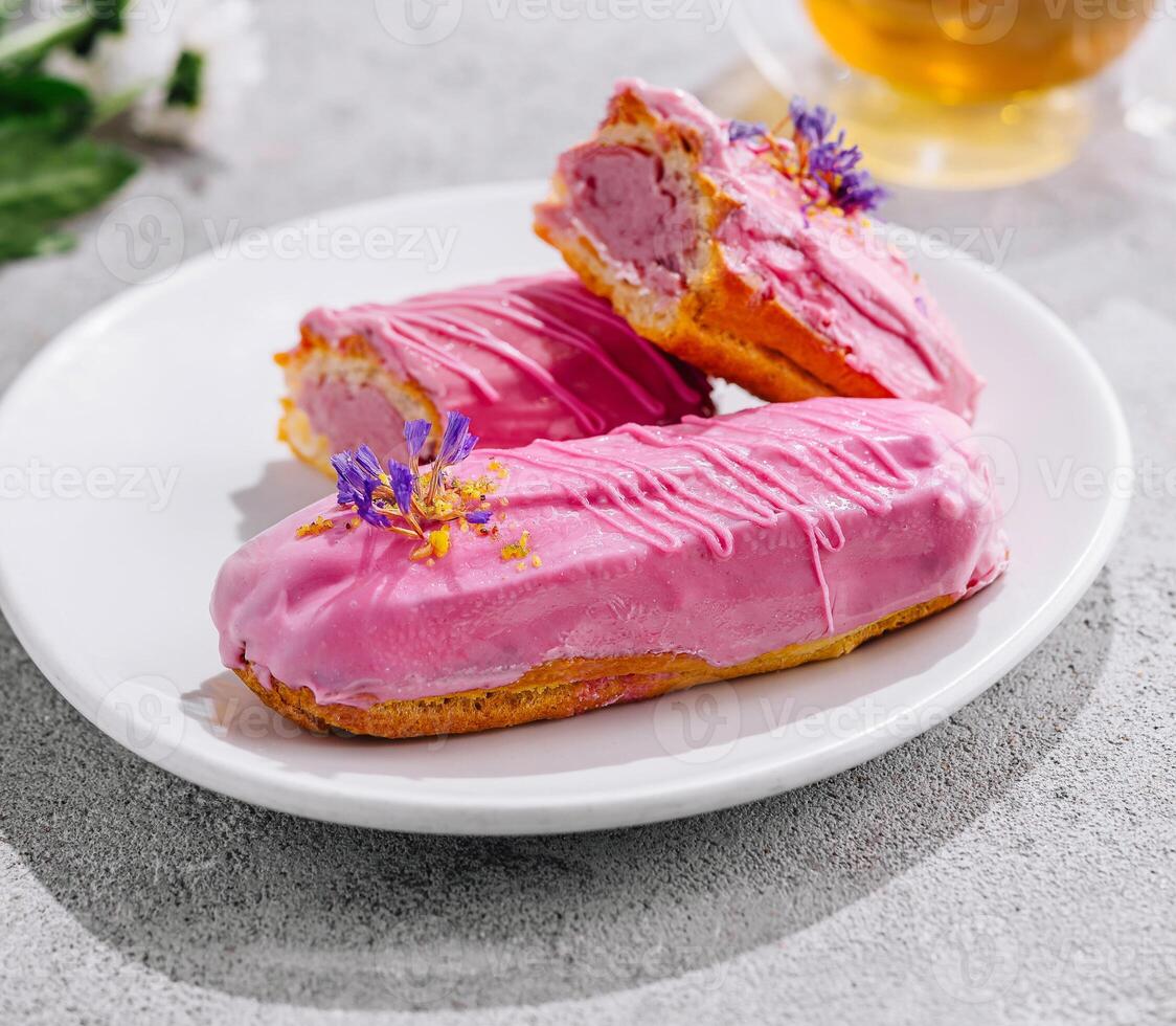 Eclairs with pink glaze and tea photo