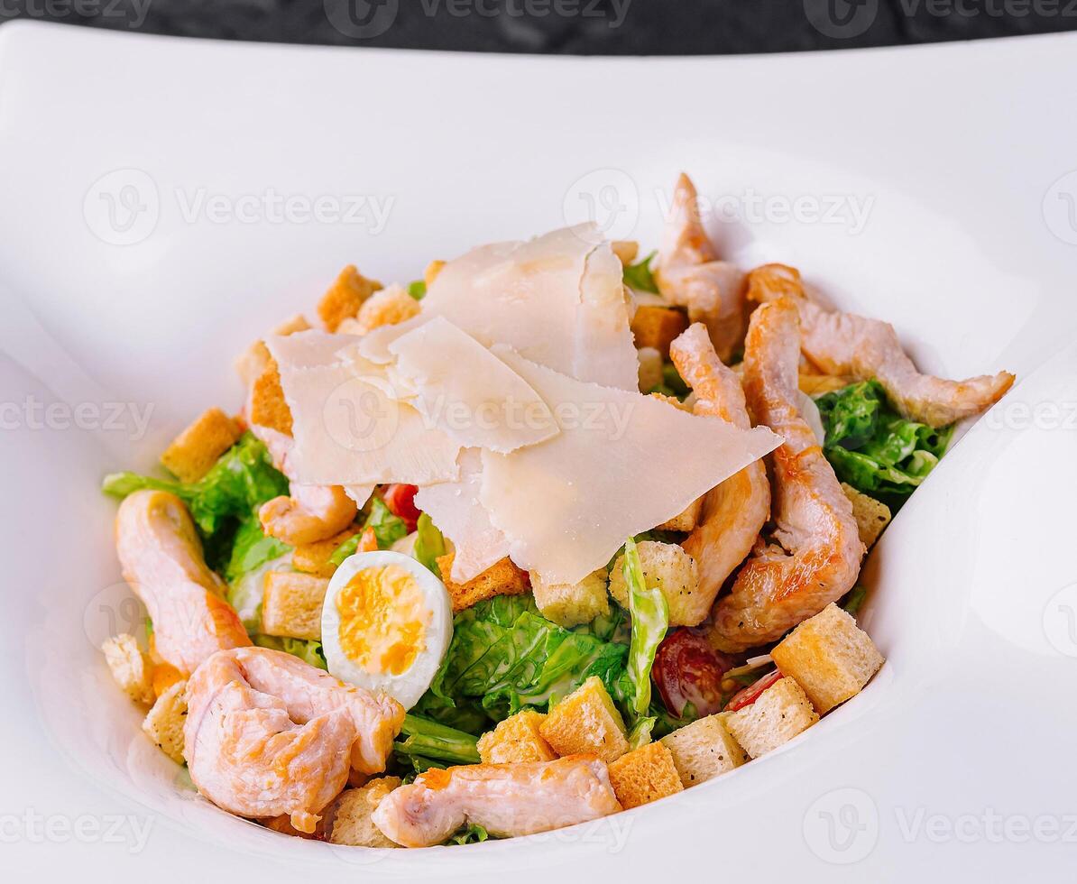 Caesar salad with grilled chicken meat, fresh lettuce, parmesan cheese and fried croutons photo