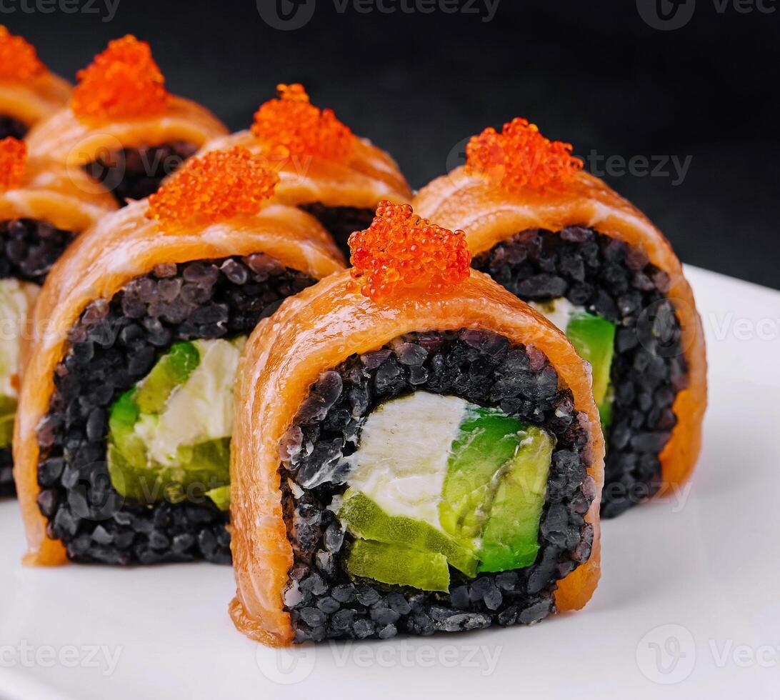 Black rice sushi rolls with salmon on white plate photo