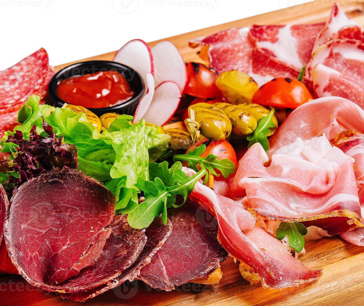 Variety of meats, sausages, salami, ham, olives, laid out on a wooden board photo