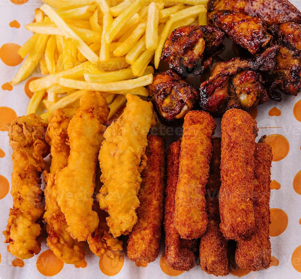fried nuggets and spicy chicken legs, wings and french fries potatoes photo