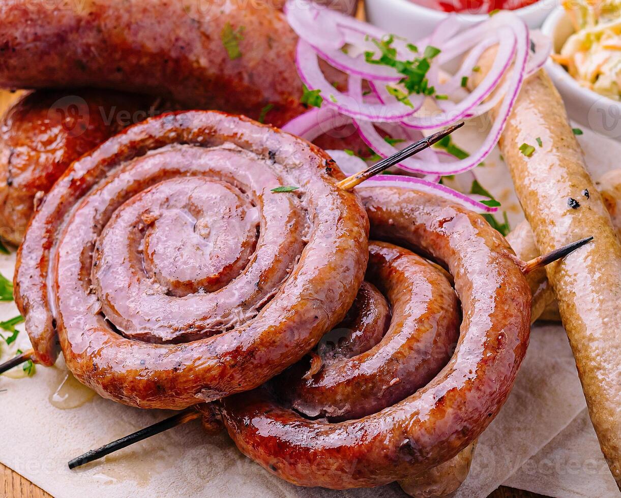 Grilled sausages on a wooden board with sauce photo