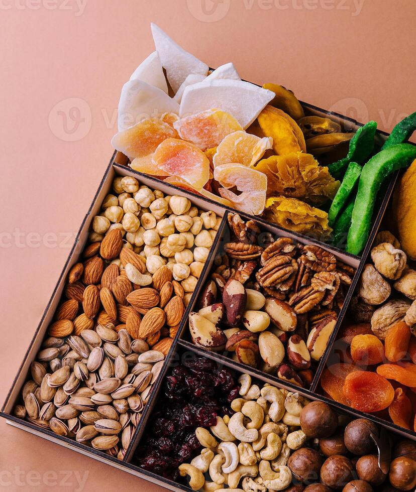Assorted nuts and dried tropical fruits in a wooden box photo