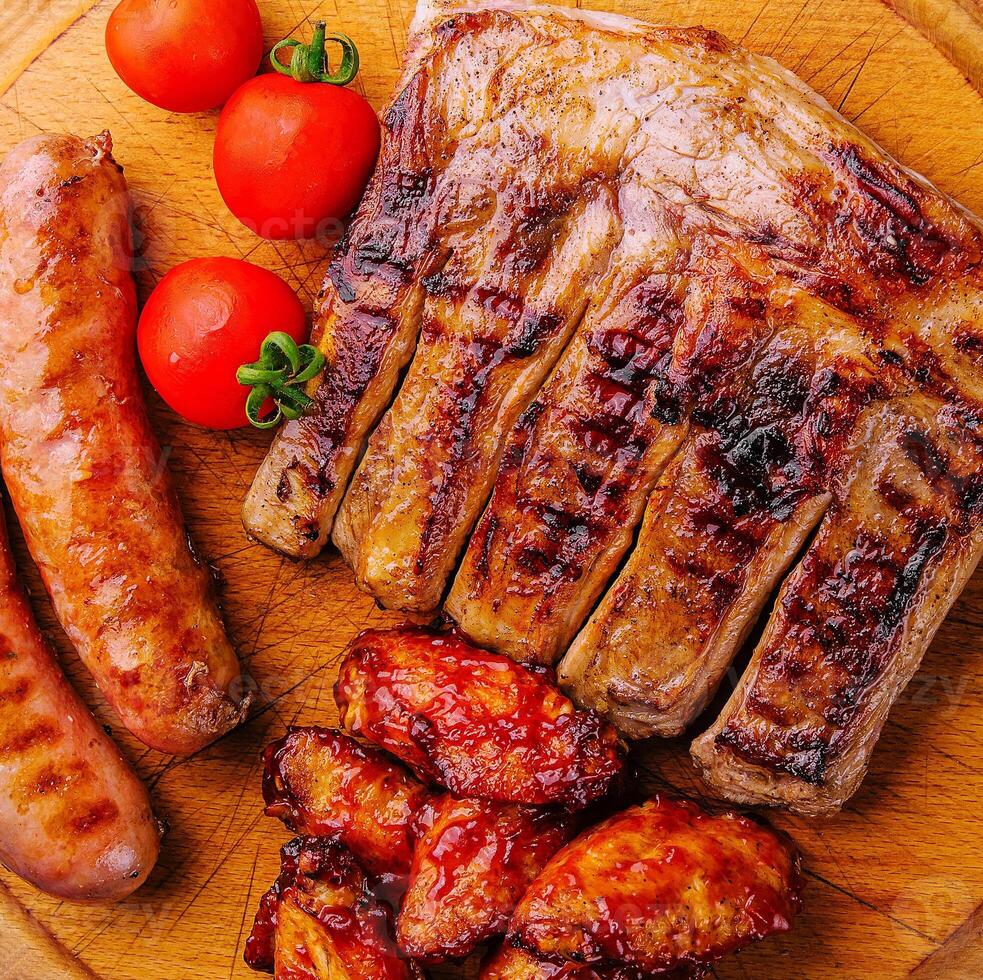 pork ribs with chicken and sausages on wooden board photo