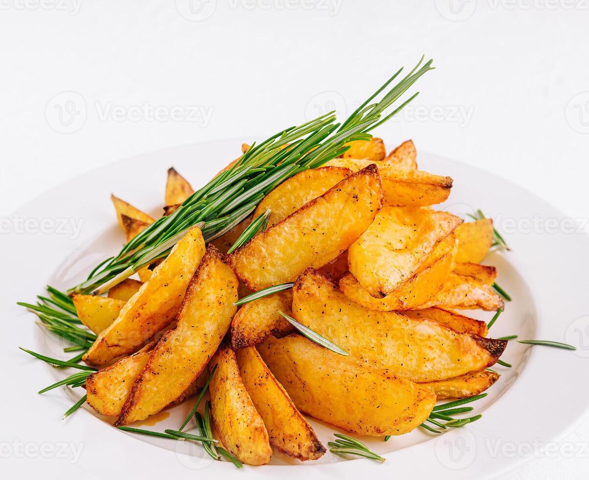 Baked potato wedges with rosemary on plate photo