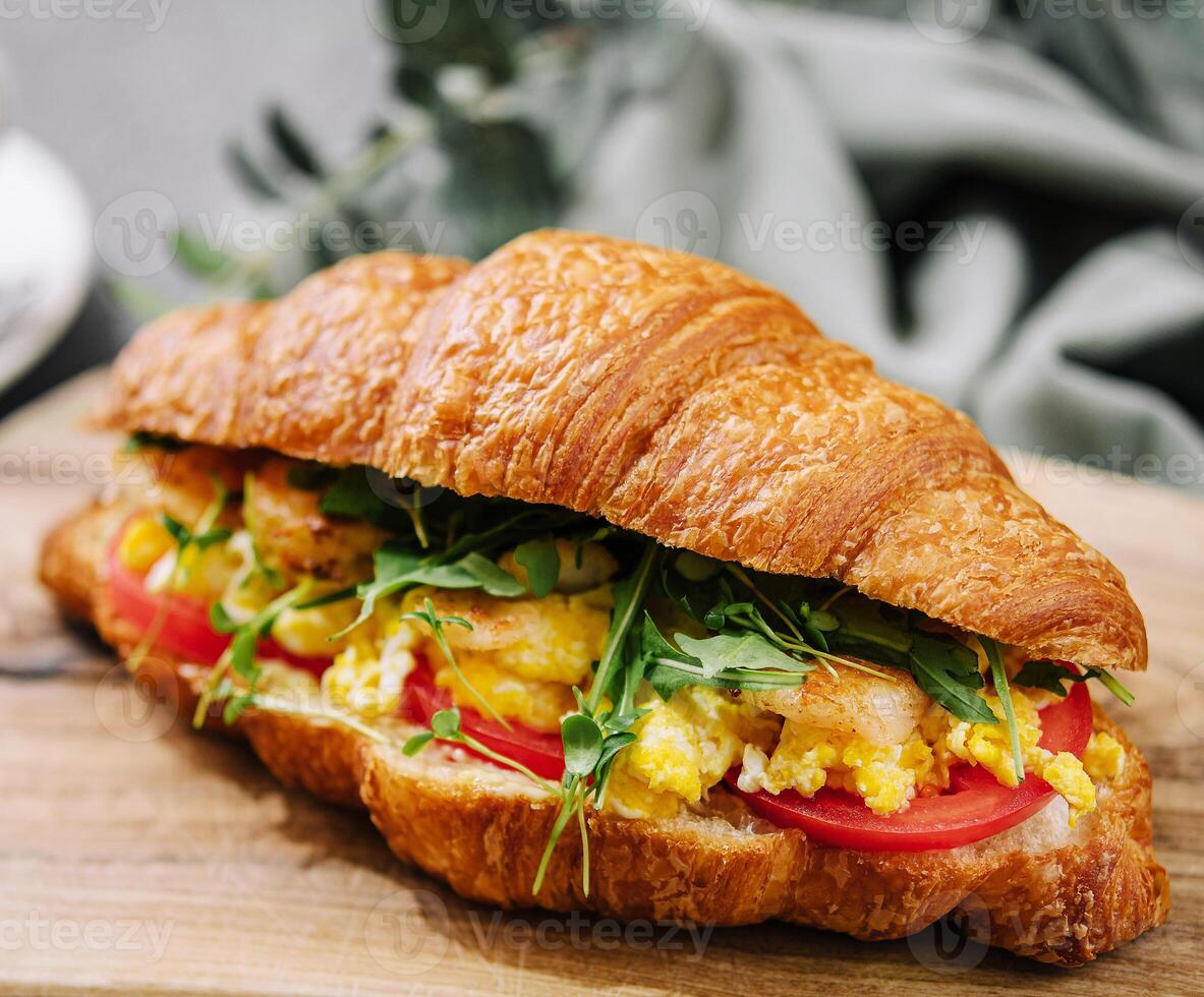 Croissant stuffed scrambled eggs with shrimps photo