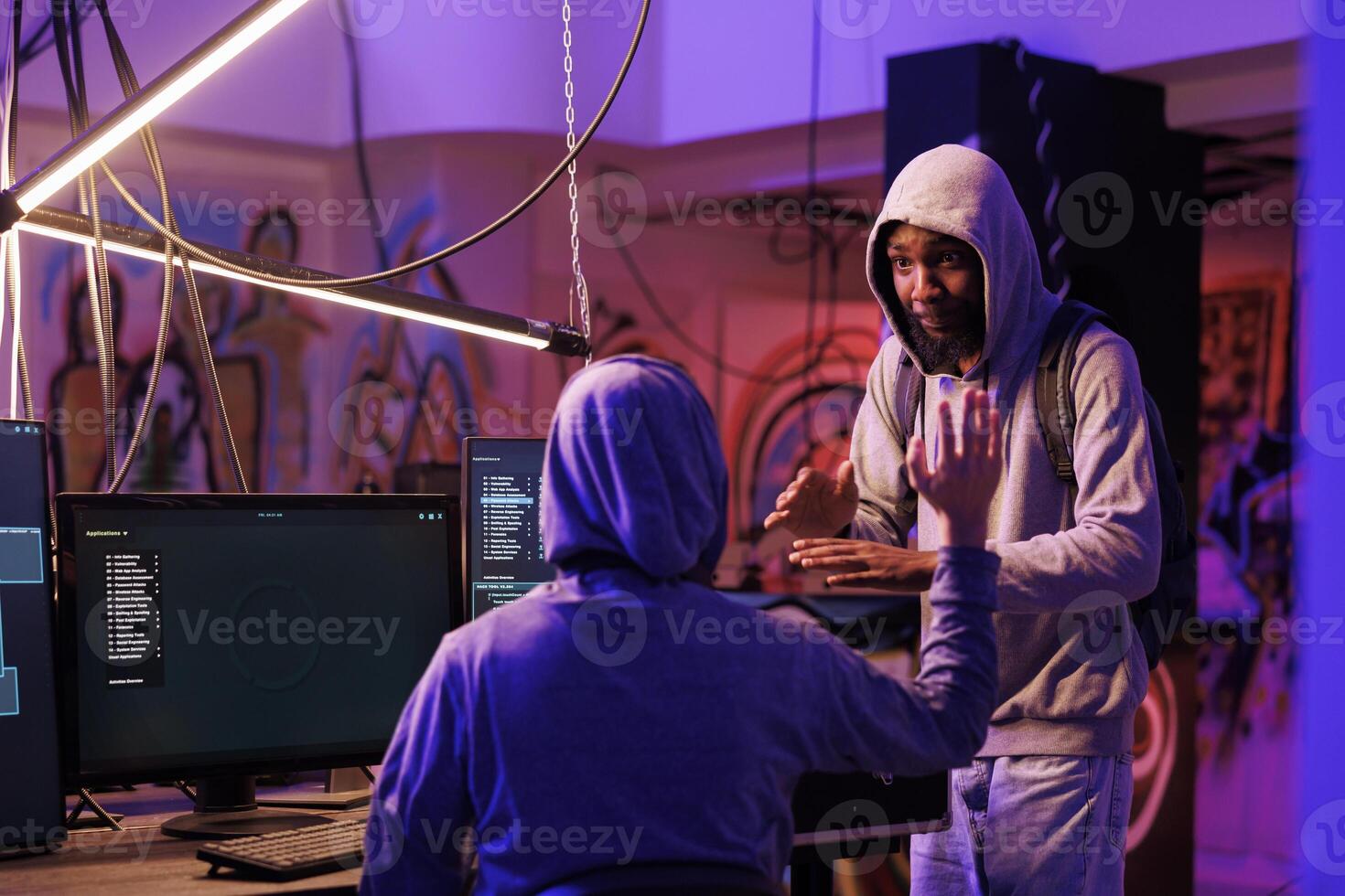 Smiling african american criminal discussing plan to break into computer network system. Two cheerful hackers talking about ransomware attack on company database to steal confidential information photo