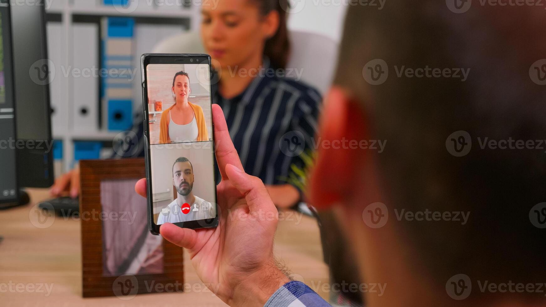 Entrepreneur talking on videocall with company manager and executive administrator sitting on desk in corporate building office using smartphone. Financial businessman using modern technology. photo