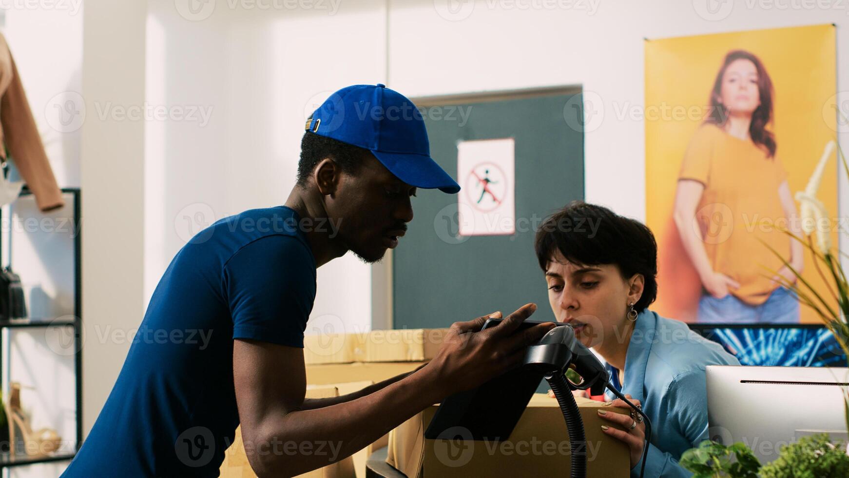 African american courier discussing shipping details with store manager, showing delivery report on tablet computer in modern boutique. Employee preparing customers packages in shopping centre photo