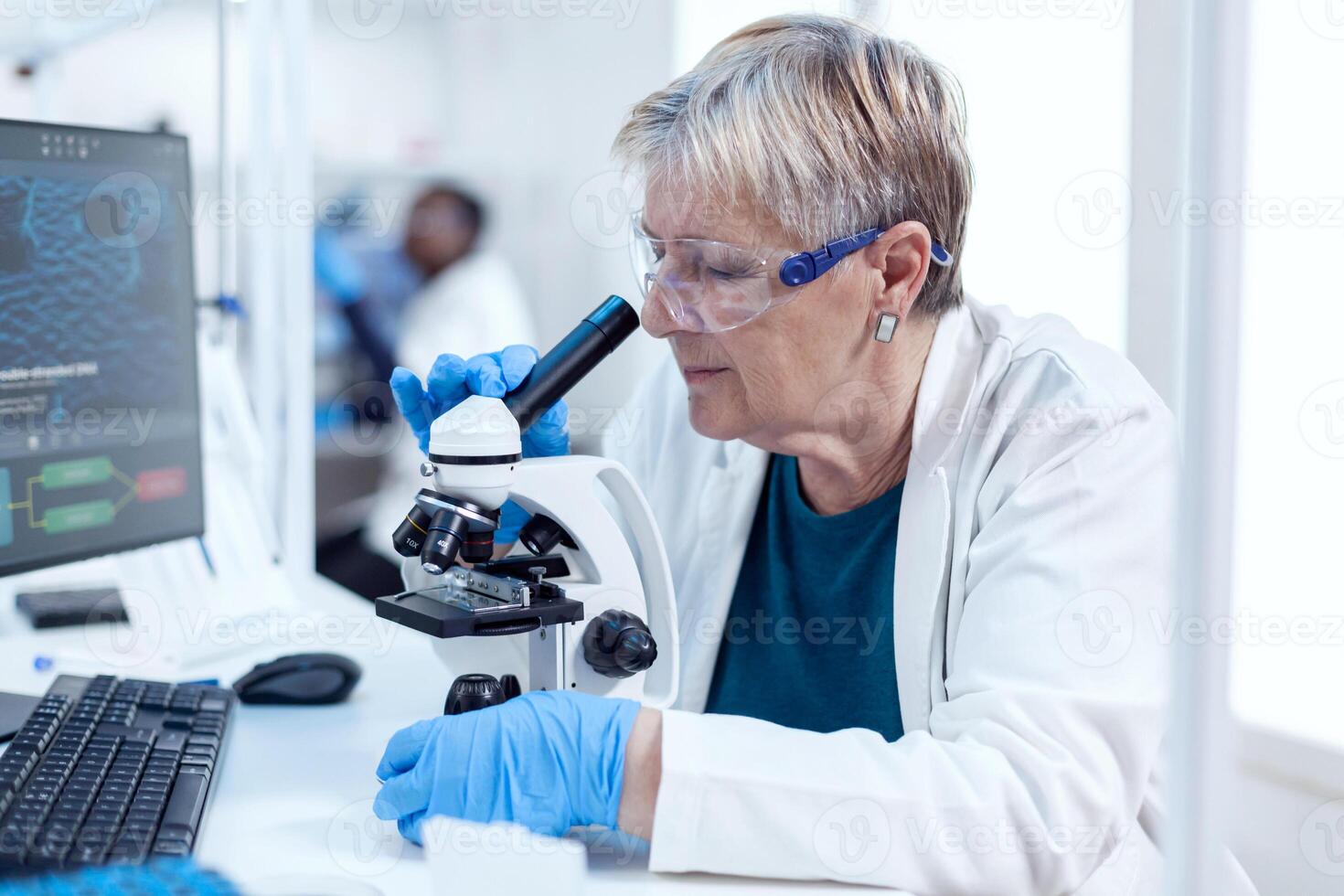 Senior chemist scientist doing genetic investigation using microscope. Elderly researcher carrying out scientific research in a sterile lab using a modern technology. photo