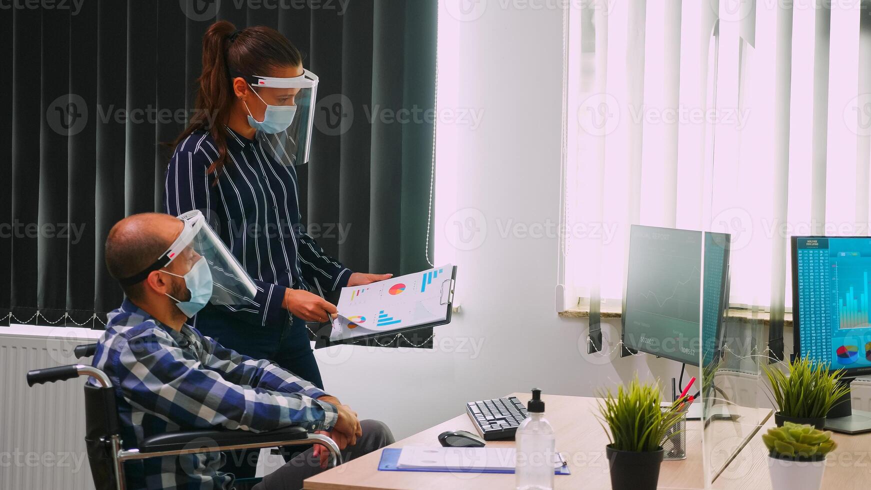 Business people wearing protective mask in new normal office discussing strategy, businessman sitting in wheelchair. Team working in profesional workspace in corporate company during covid-19 pandemic photo