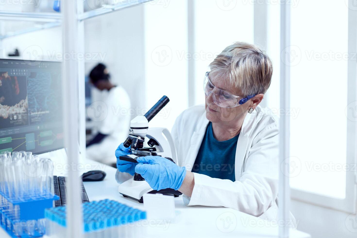 mayor científico poniendo vaso diapositiva en microscopio durante médico investigación. mayor investigador que lleva fuera científico investigación en un estéril laboratorio utilizando un moderno tecnología. foto