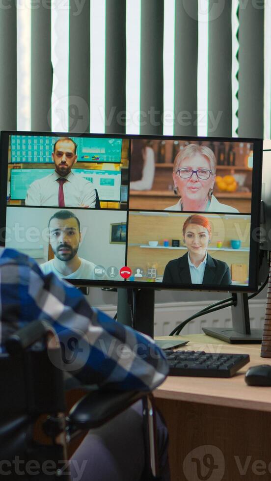 Handicapped disabled manager in wheelchair talking during videocall having online conference in business office. Paralysed, immobilized freelancer working in financial company using modern technology. photo