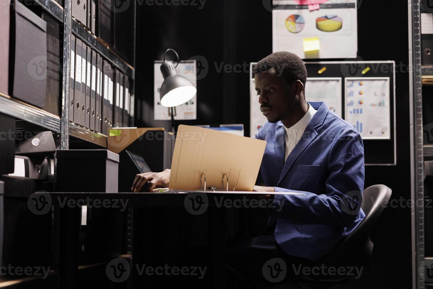 Corporate employee working at accountancy record, reading management documents in arhive room. African american businessman checking administrative report, analyzing bureaucracy files photo