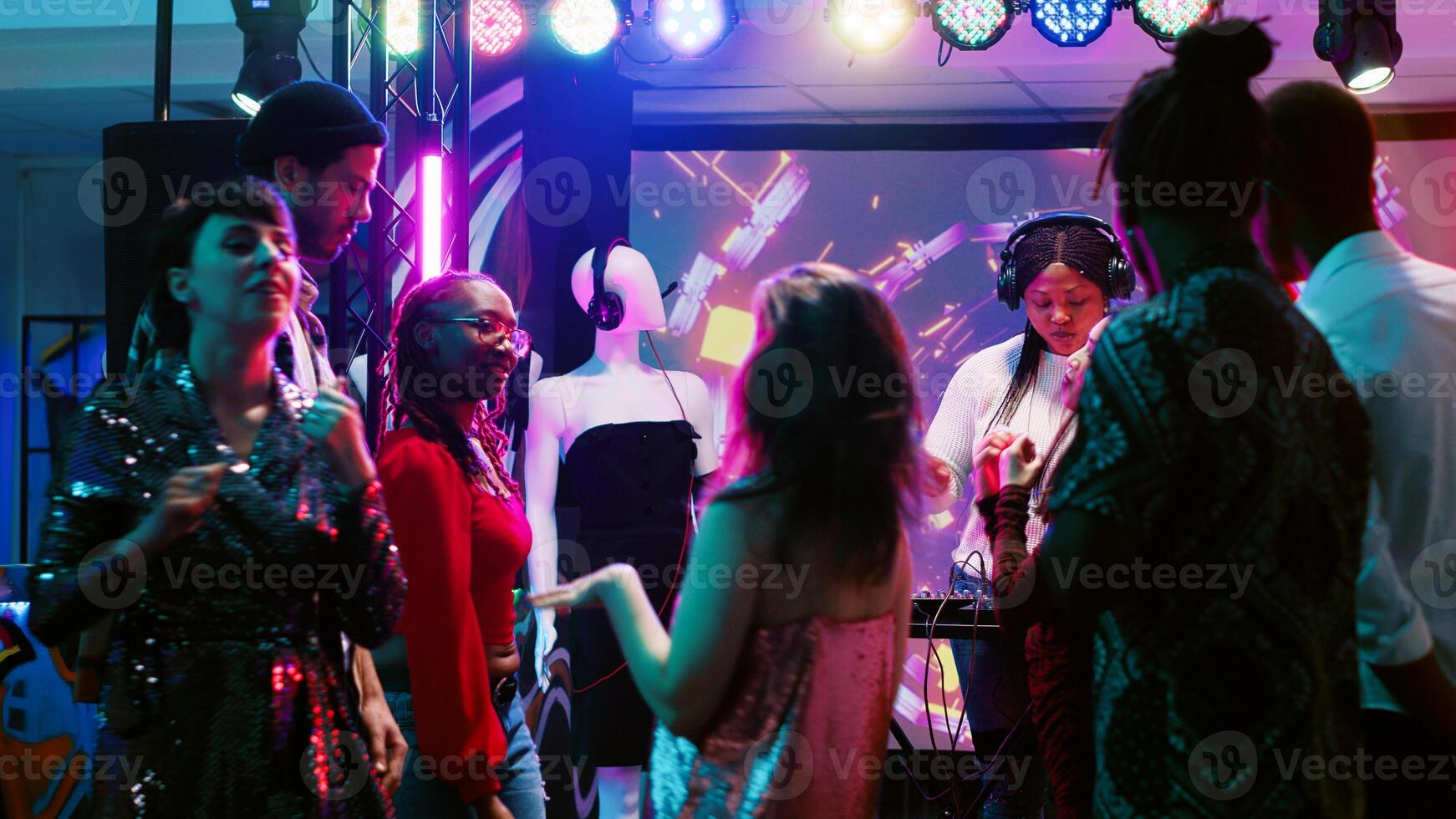 Modern woman using DJ panel on stage and creating live electronic music at club party, audio clubbing equipment. Funky girl with headset mixing music for people on the dance floor. photo