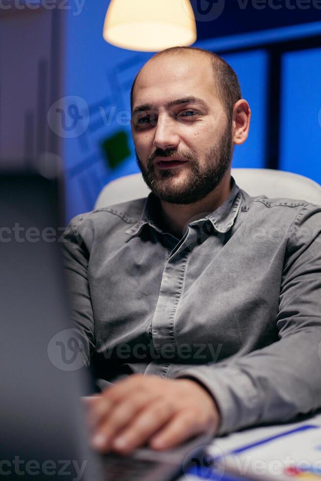 Close up of entrepreneur reading article on laptop doing overtime to finish a project Smart businessman sitting at his workplace in the course of late night hours doing his job. photo