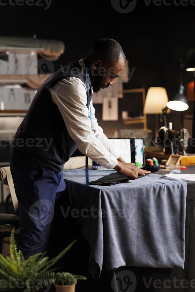 Expert suitmaker meticulously working on suit blazer in atelier shop workspace with precision and expertise. Professional fashion designer finishing sartorial business attire for client comission photo