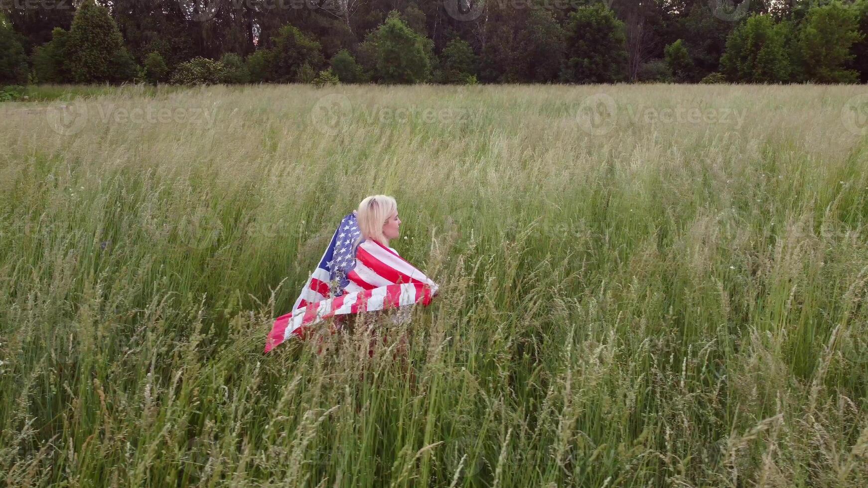 American woman proudly holding American flag at sunset field, celebrate 4th of July photo