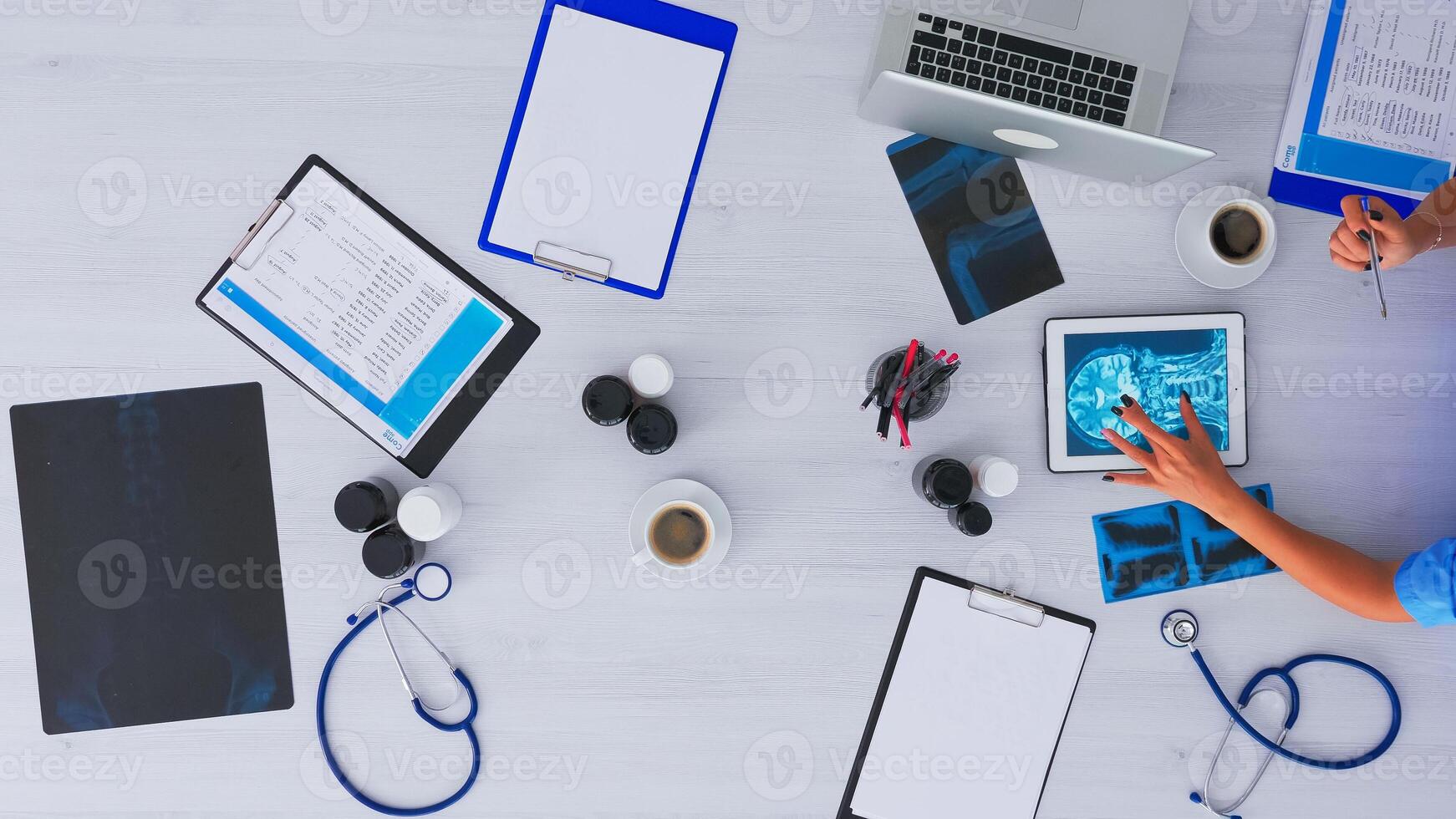 parte superior ver de enfermero analizando humano cerebro utilizando tableta en flatlay sentado en escritorio en clínica con radiografía y digital dispositivos. asistente tomando notas en portapapeles, investigando en Copiar espacio foto