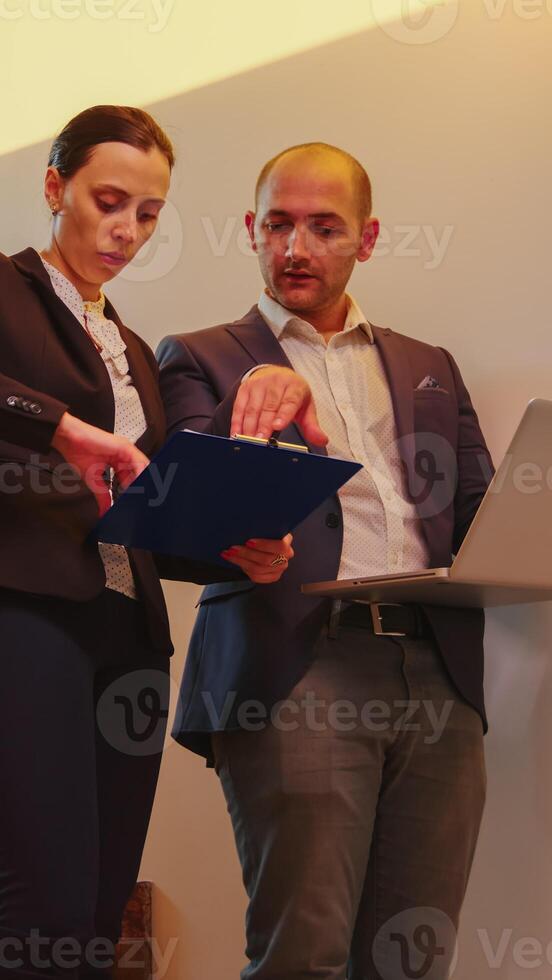 Businesswoman talking with corporate executive manager on staircase of business building looking on laptop. Professional successful entrepreneur in team working overtime in modern office stairs. photo