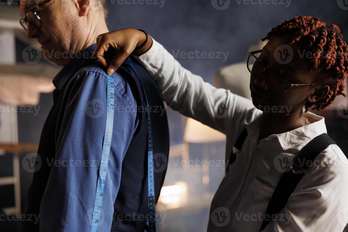 Elderly customer getting arm measurements taken by meticulous tailor in atelier shop. Experienced seamstress sizing up client proportions for custom made sartorial costume piece comission, close up photo