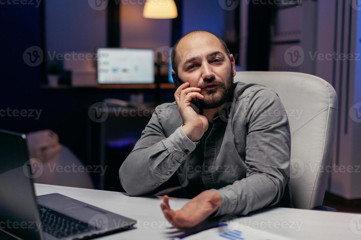 Businessman discussing with client in the course of corporate call. Manager having a business conversation using smartphone while working overtime at the office. photo