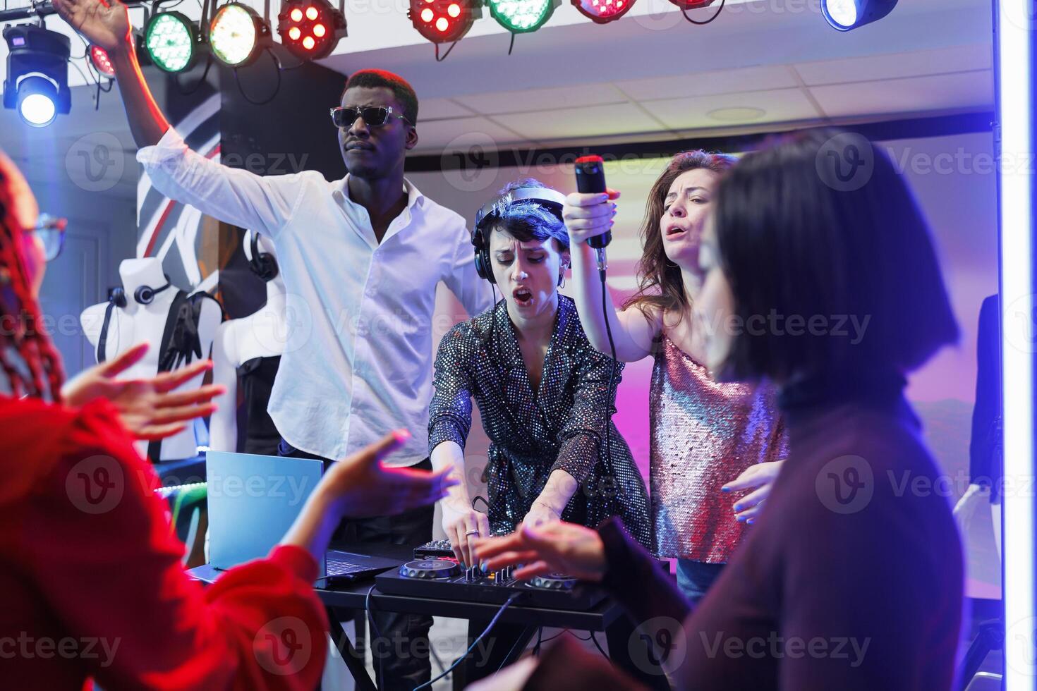 electrónico música banda ejecutando en etapa en Club nocturno, mientras personas ir de fiesta en pista de baile. mujer DJ utilizando pistas mezclador y cantante dando mic a emocionado concurrido a canta a lo largo foto