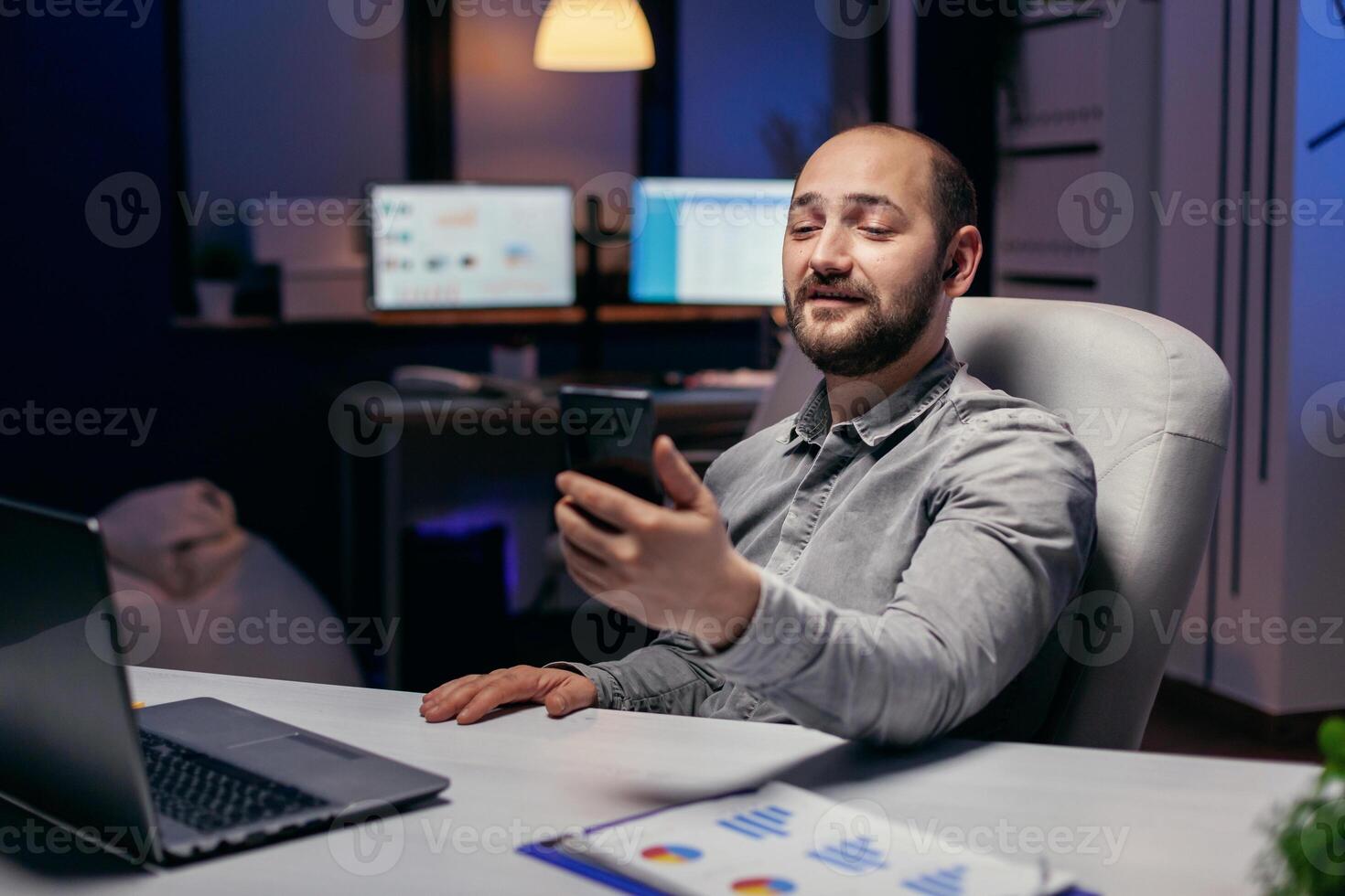 Freelancer in empty office talking on online call with someone. Businessman in the course of an important video conference while doing overtime at the office. photo