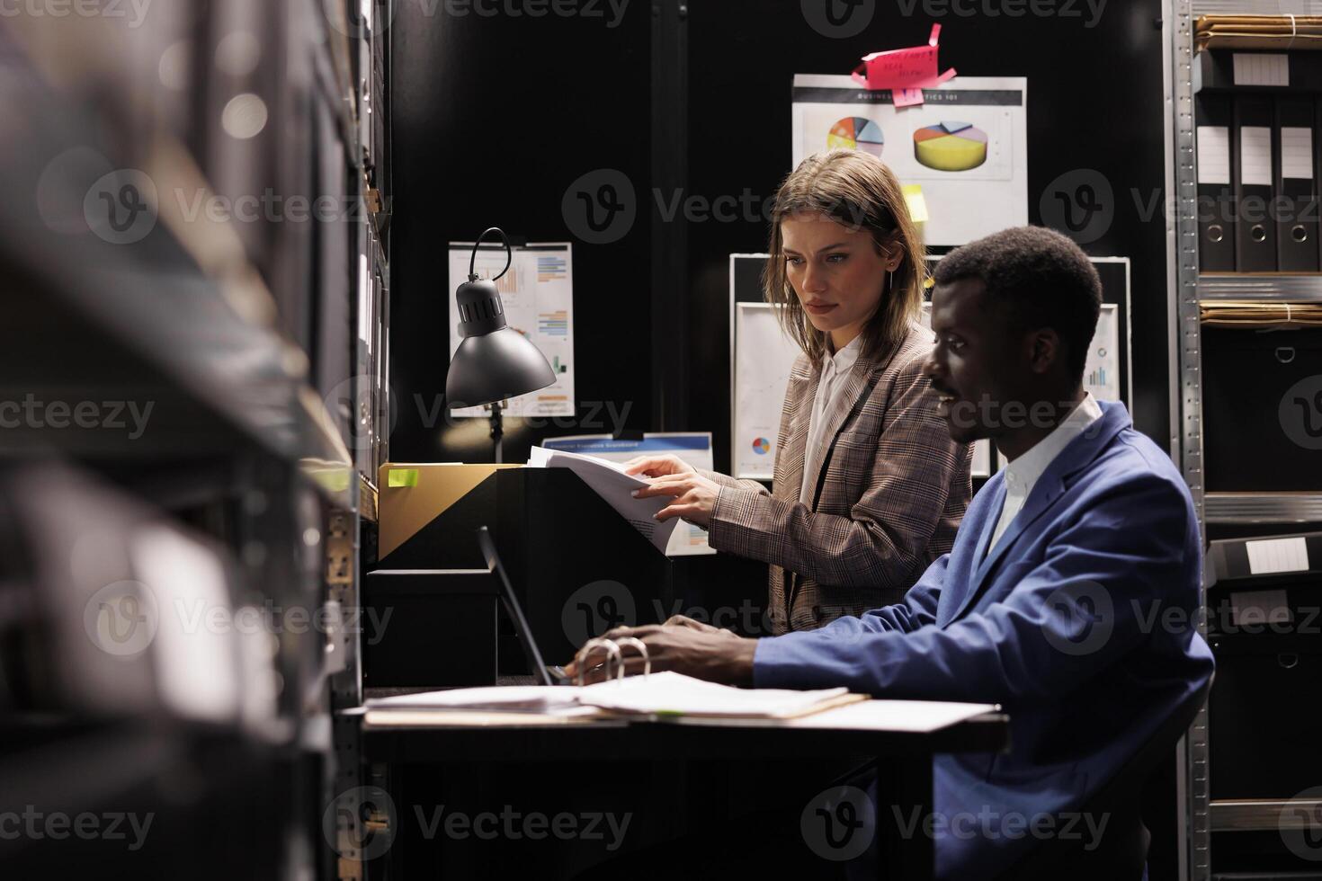 Depository workers reading administrative files, discussing bureaucracy record in storage room. Diverse bookkeepers working overtime at accountancy report, analyzing management research photo