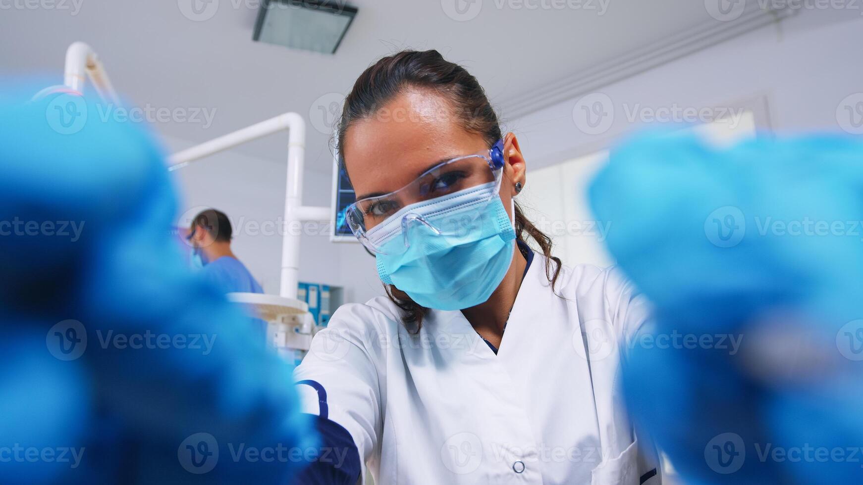 pov de paciente en un dental clínica sentado en cirugía silla mientras profesional dentista trabajando con guantes durante examen en moderno clínica utilizando esterilizado instrumentos foto