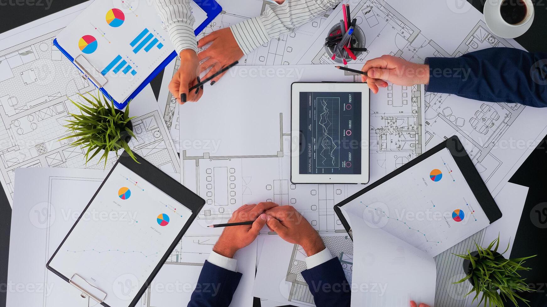 Top view of architects talking about construction plans with blueprint, analysing annual financial reports. Businesspeople designers discussing in office using digital gadgets and papers working. photo