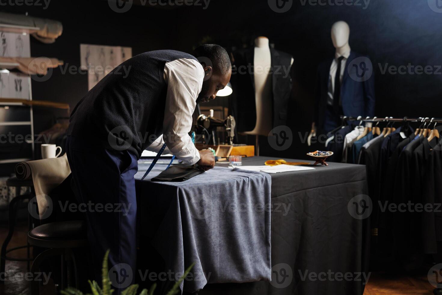 Meticulous suitmaker focused on perfecting client comissioned exquisite suit blazer for upcoming wedding. Couturer working on bespoke sartorial attire in professional tailoring shop photo