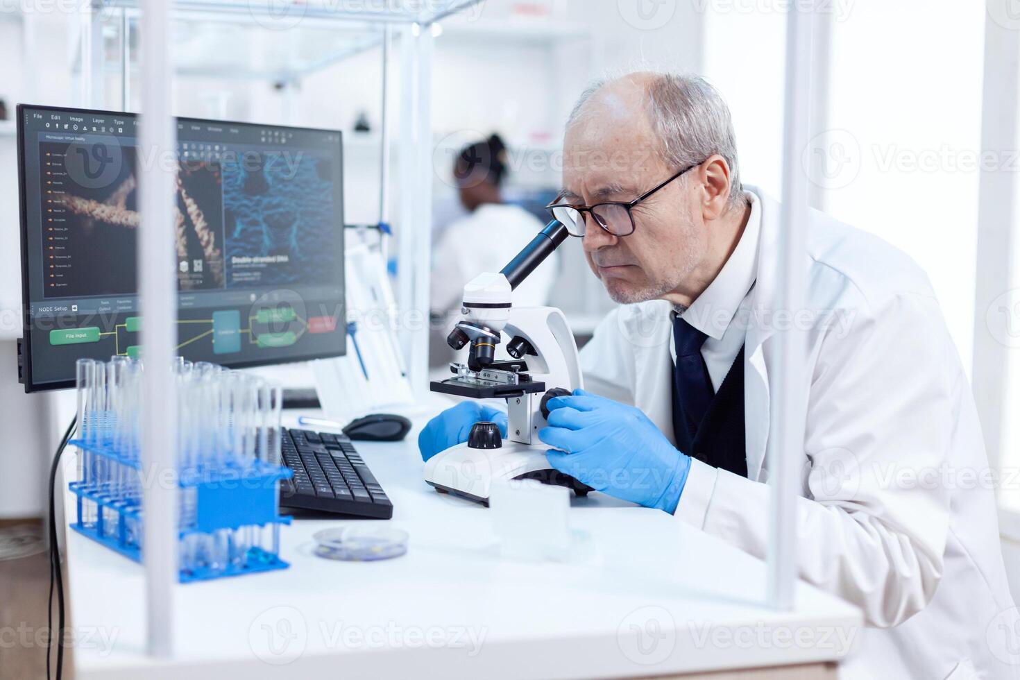 Senior scientist in chemistry laboratory uses microscope working on new medicine. Chemist researcher in sterile lab doing experiments for medical industry using modern technology. photo