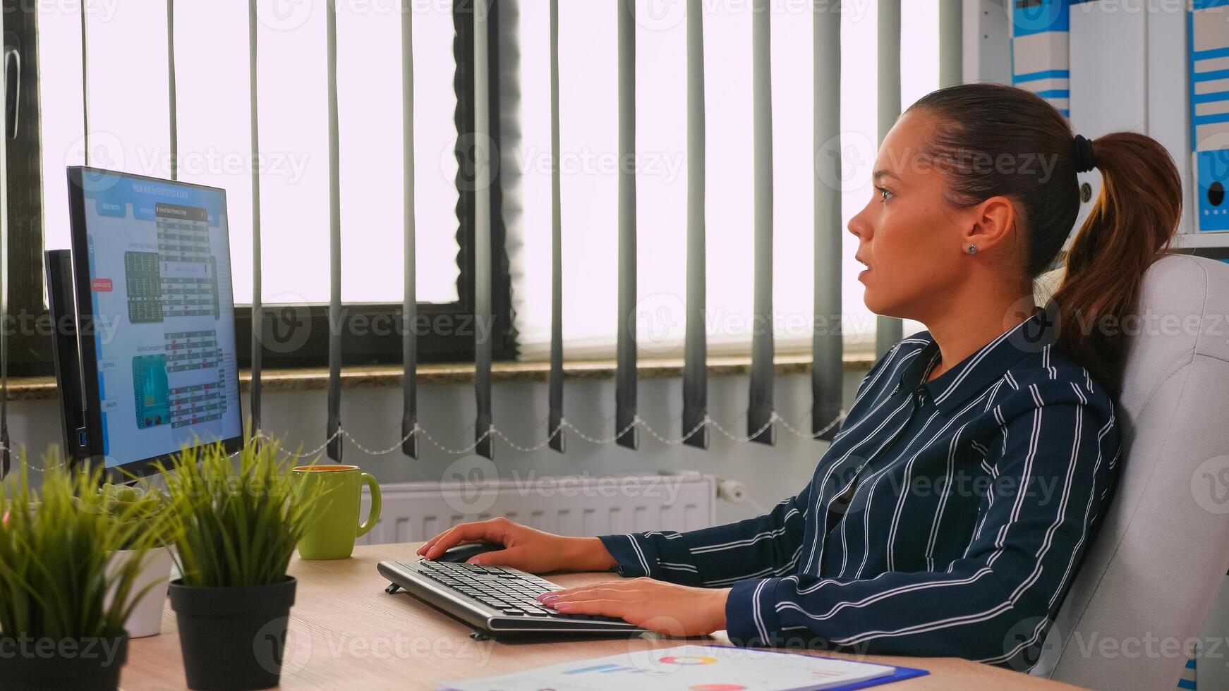 Business woman typing on computer in modern office room. Hispanic entrepreneur working in professional workspace, in personal corporate company writing on computer keyboard looking at desktop photo