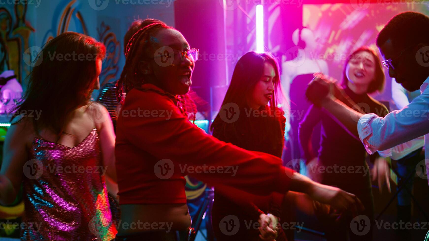 Young people jumping around at club, having fun with cool breakdance battle to show off moves on dance floor. Group of adults enjoying dancing party with live DJ music. Handheld shot. photo
