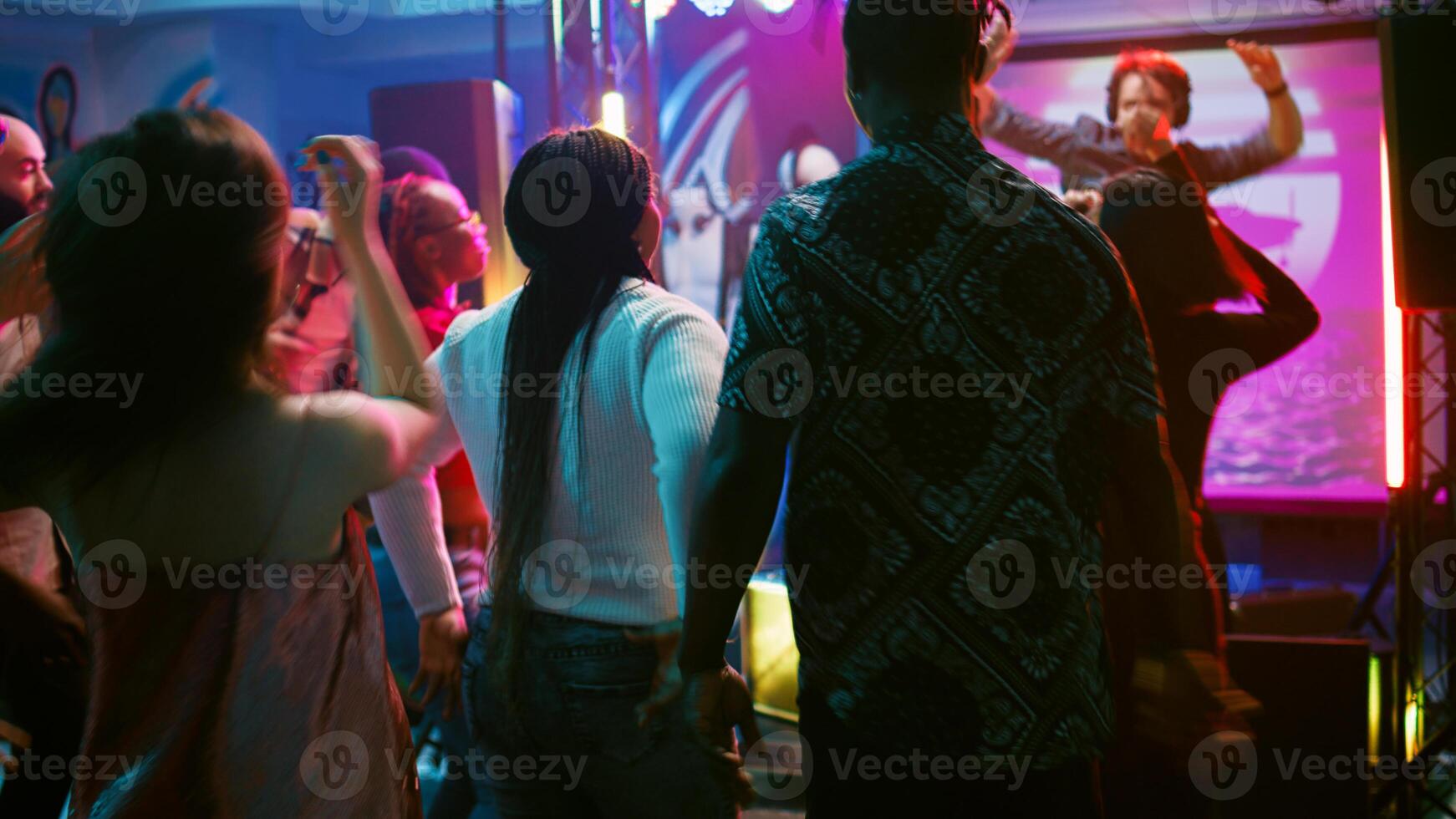 Diverse people enjoying night at club, dancing on electronic music and having fun. Group of friends feeling cheerful and showing cool funky moves on dance floor, partying. Handheld shot. photo