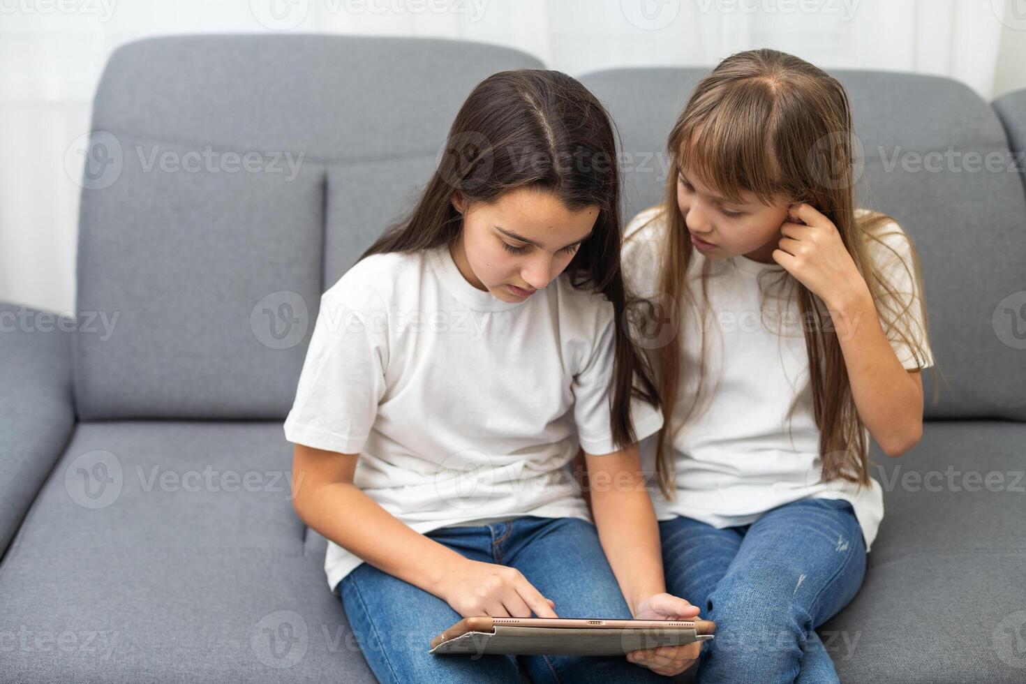 Shocked sisters using digital tablet on sofa at home photo