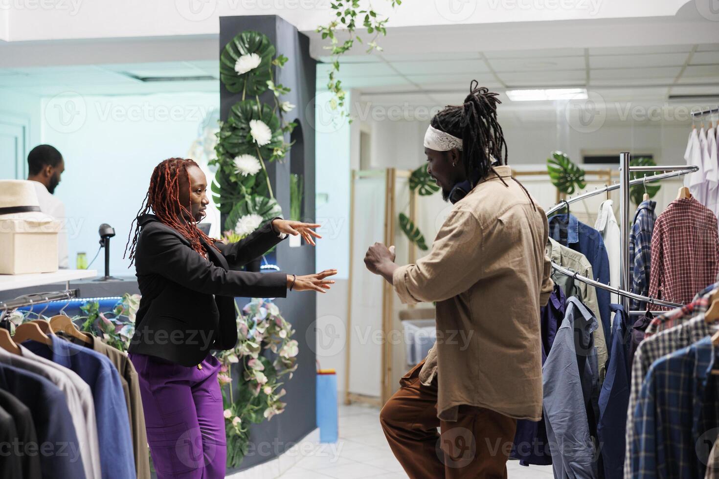 africano americano amigos disfrutando compras día y teniendo divertido en ropa almacenar. despreocupado hombre y mujer Pareja bailando mientras compras para de moda vestir en centro comercial Moda boutique foto