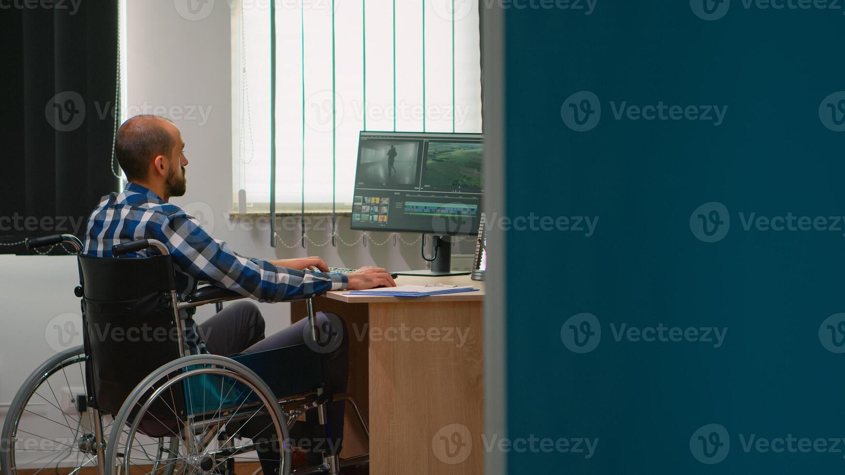 persona de libre dedicación foto diseñador con invalidez en silla de ruedas edición enviar producción un vídeo proyecto creando contenido en moderno empresa oficina. camarógrafo trabajando desde foto estudio.