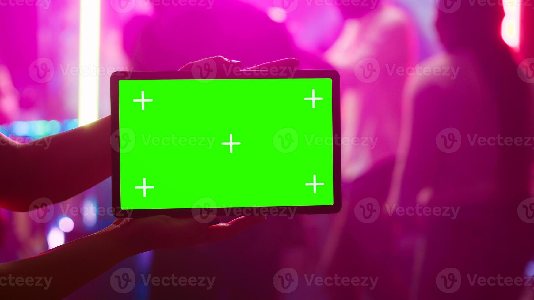Person showing tablet with greenscreen at nightclub, being on the dance floor holding device with mockup template. Girl looking at isolated chroma key display with blank copyspace. photo